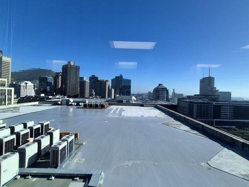 Elevated city view from an office window overlooking surrounding commercial buildings and rooftop HVAC infrastructure.