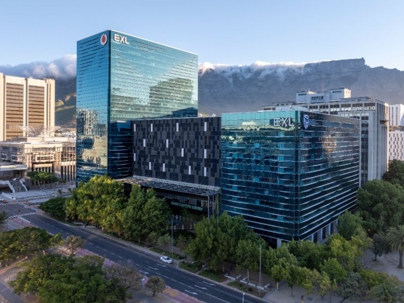 Aerial view of a modern commercial office complex featuring glass curtain wall facades, situated in an urban environment with surrounding greenery.