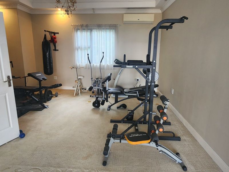 A dedicated home gym space featuring crown molding, a chandelier, and a wall-mounted air conditioning unit.