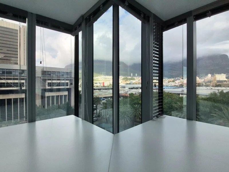 Modern corner office space featuring expansive floor-to-ceiling windows with panoramic city and mountain views.