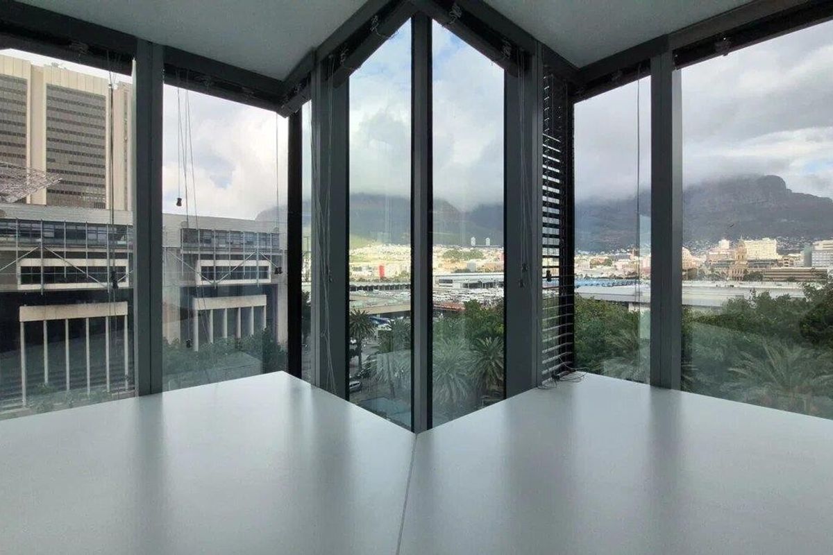 Modern corner office space featuring expansive floor-to-ceiling windows with panoramic city and mountain views.