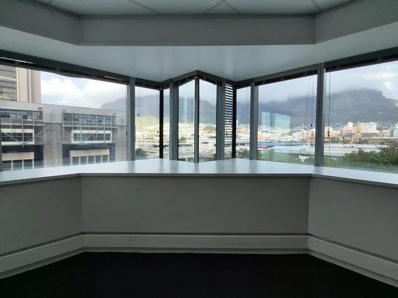 Empty office space featuring expansive floor-to-ceiling windows with panoramic city and mountain views, providing excellent natural light and a professional atmosphere.