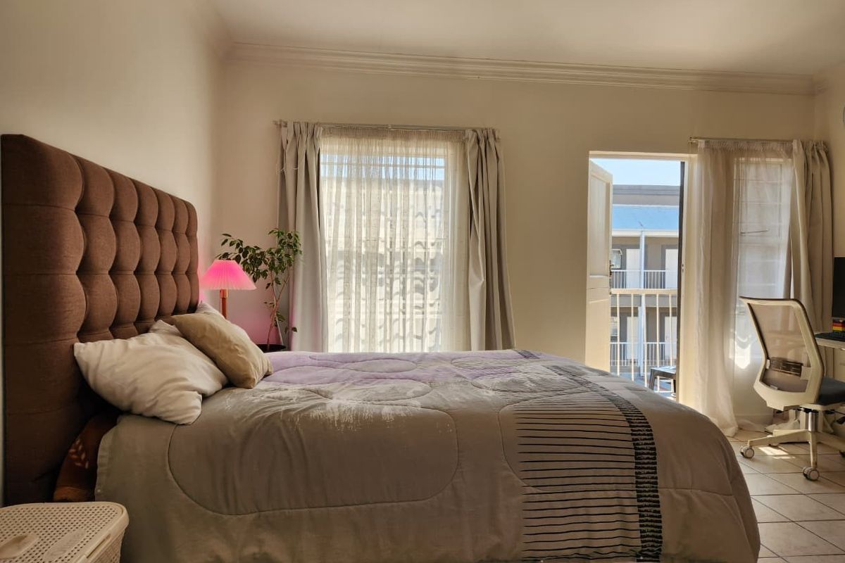 A bedroom featuring tiled flooring, decorative cornicing, and direct access to an outdoor balcony area.