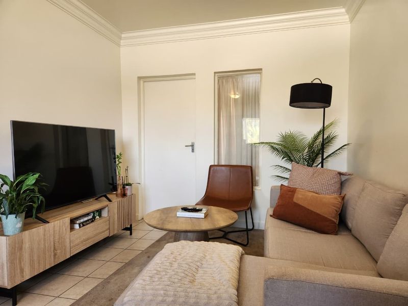 A cozy living room featuring neutral tiled flooring and classic crown molding, creating a comfortable and well-maintained space.