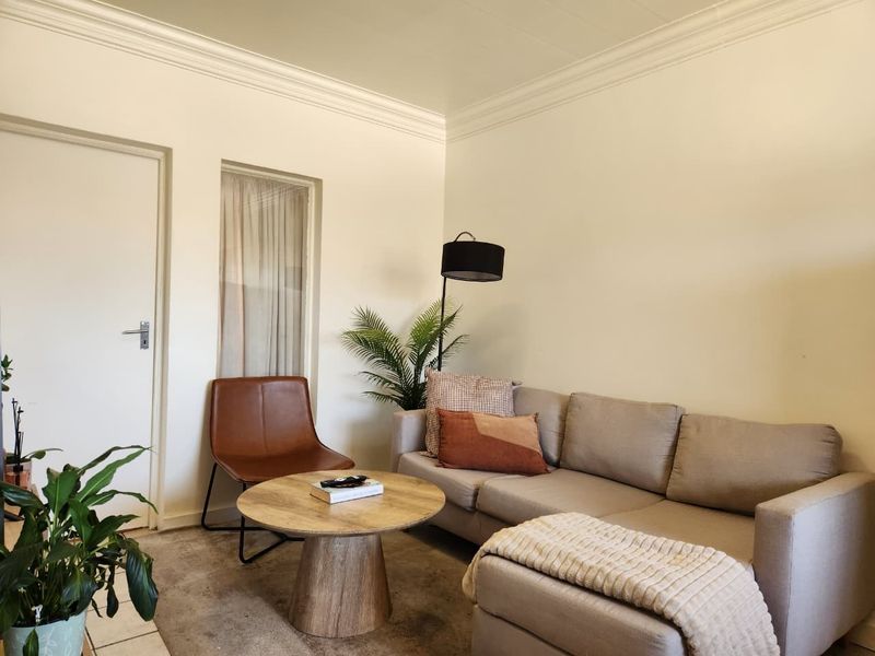 A cozy living room featuring crown molding, neutral walls, and carpeted flooring, providing a comfortable and inviting space for relaxation.