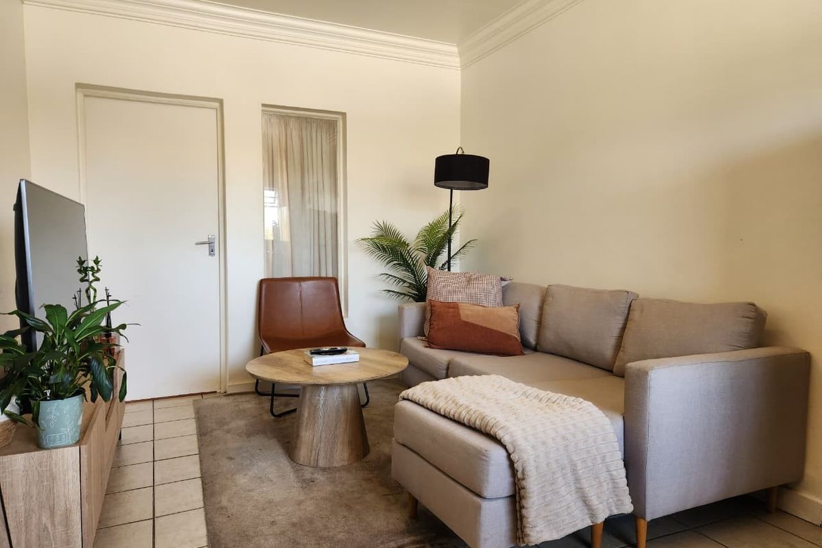 A cozy living room featuring tiled flooring, crown molding, and a neutral color palette, providing a comfortable and functional space.