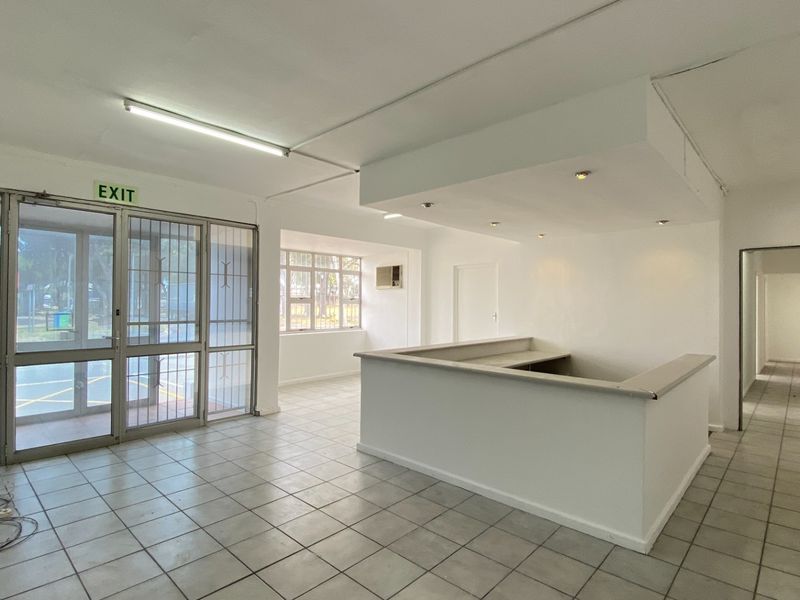 Spacious industrial entry area featuring a built-in reception counter, tiled flooring, secure glass entrance, and ample natural light through large windows.