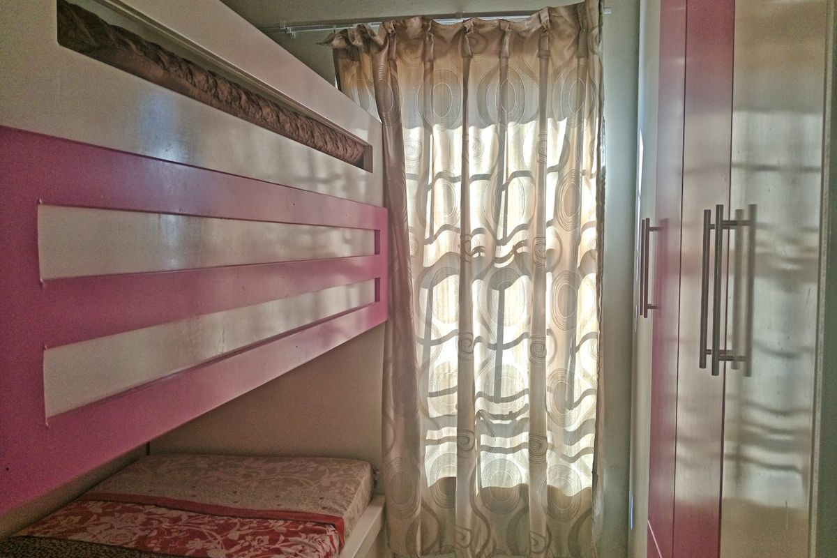 A compact bedroom featuring a built-in bunk bed and integrated wardrobe storage, maximizing space efficiency.