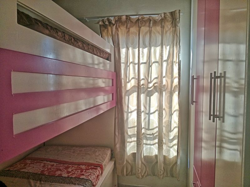 A compact bedroom featuring a built-in bunk bed and integrated wardrobe storage, maximizing space efficiency.