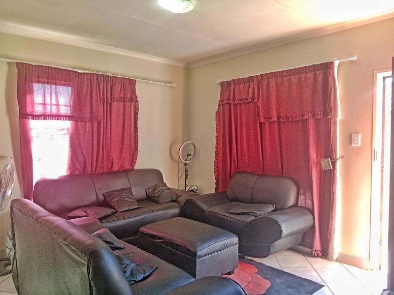 A living room area featuring tiled flooring and dual window treatments, providing a functional space for relaxation.