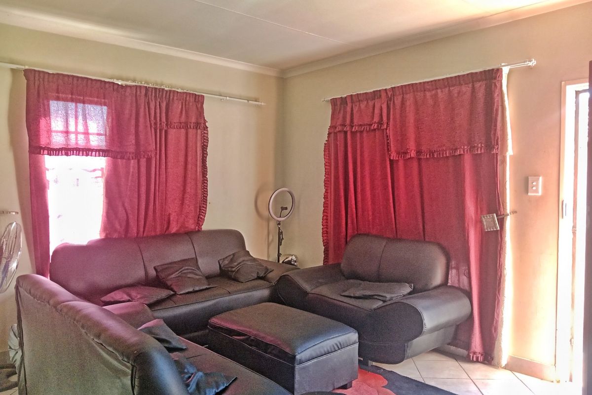A living room area featuring tiled flooring and dual window treatments, providing a functional space for relaxation.