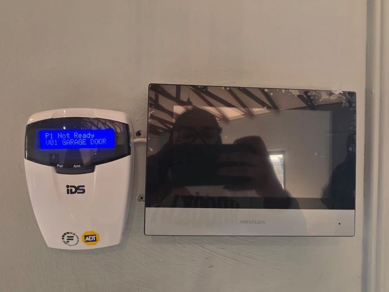 Wall-mounted security alarm keypad and intercom monitor system installed in the interior.