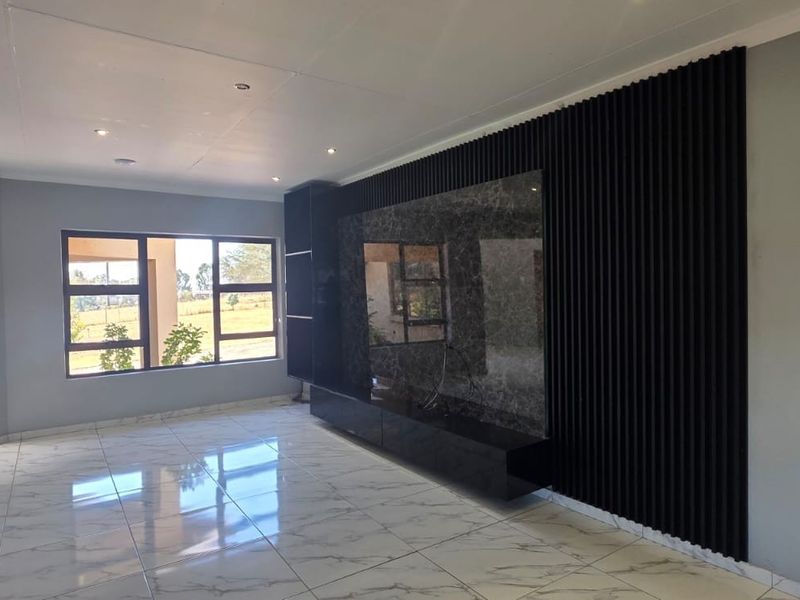 Spacious living area featuring modern marble-look floor tiles, recessed lighting, and a contemporary built-in media wall with a decorative slatted timber feature.