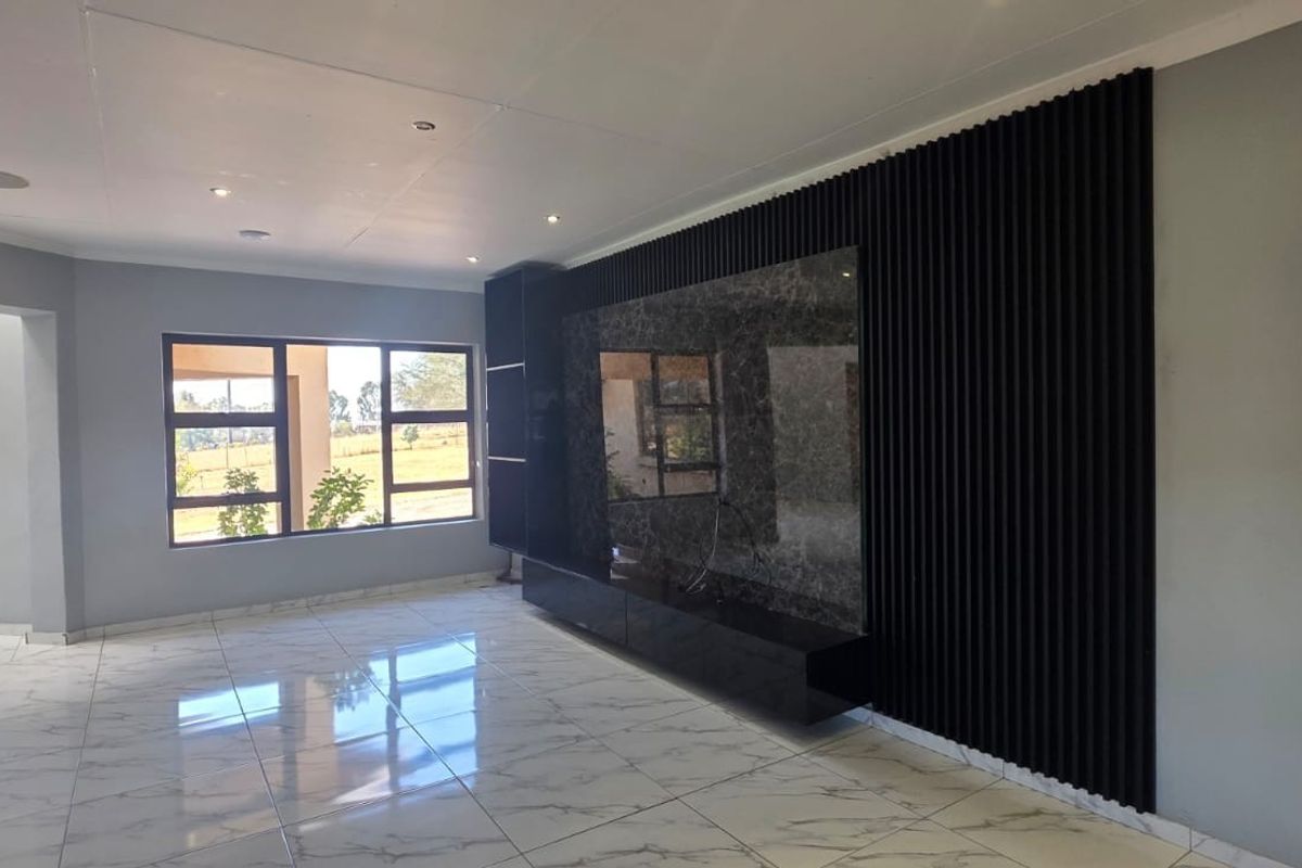 Spacious living area featuring modern marble-look floor tiles, recessed lighting, and a contemporary built-in media wall with a decorative slatted timber feature.