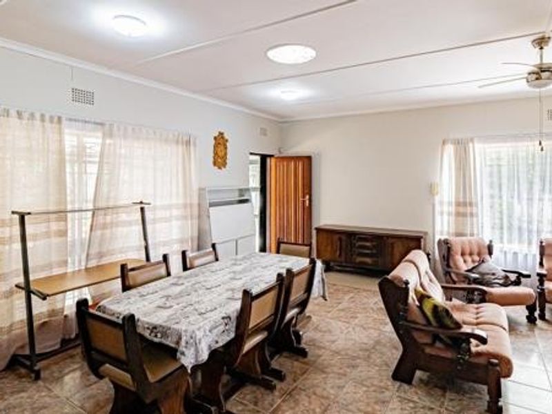 Spacious open-plan living and dining area featuring tiled flooring, ceiling fan, and ample natural light through large windows.