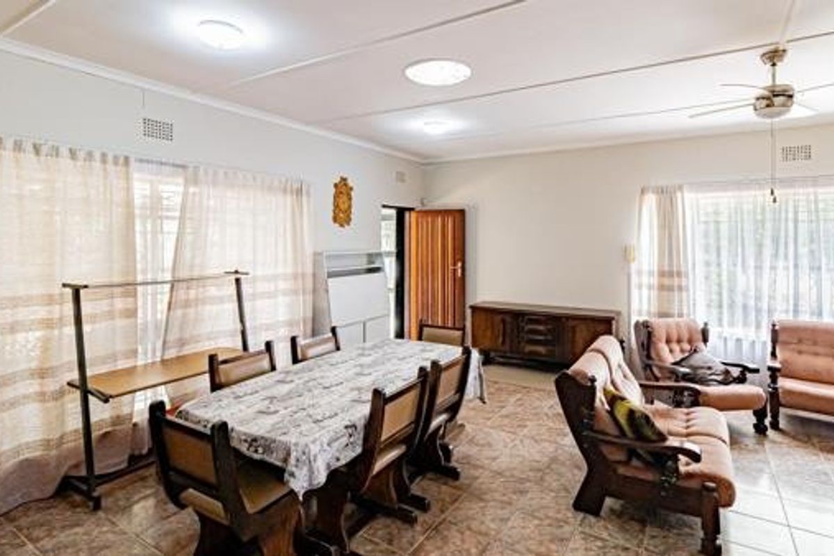 Spacious open-plan living and dining area featuring tiled flooring, ceiling fan, and ample natural light through large windows.