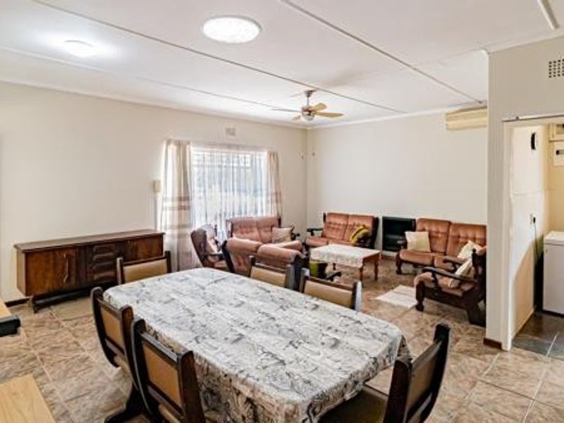 Spacious open-plan living and dining area featuring tiled flooring, ceiling fan, and air conditioning, with an adjacent utility space.