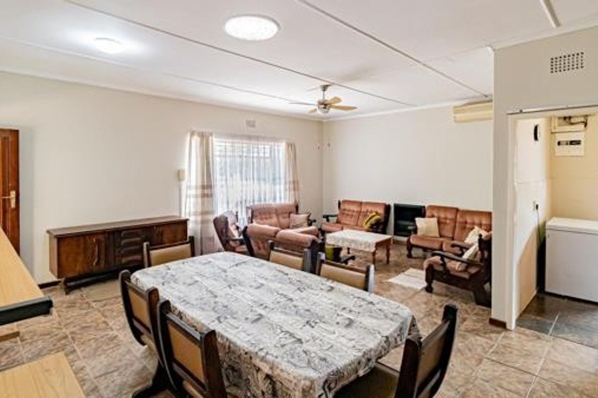 Spacious open-plan living and dining area featuring tiled flooring, ceiling fan, and air conditioning, with an adjacent utility space.