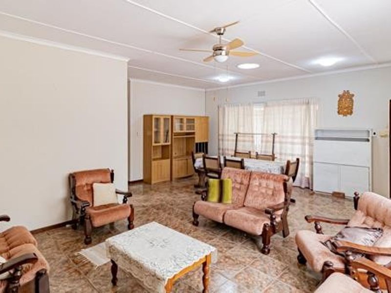Spacious open-plan living and dining area featuring tiled flooring, a ceiling fan, and direct access to an outdoor patio through a sliding door.