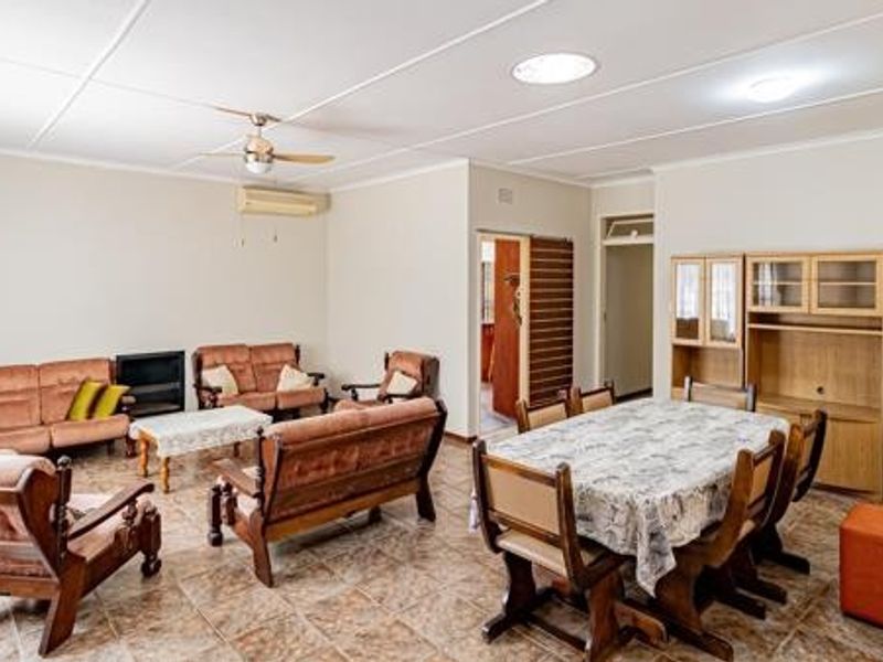 Spacious open-plan living and dining area featuring tiled flooring, a ceiling fan, and built-in cabinetry, offering a functional layout for family living.