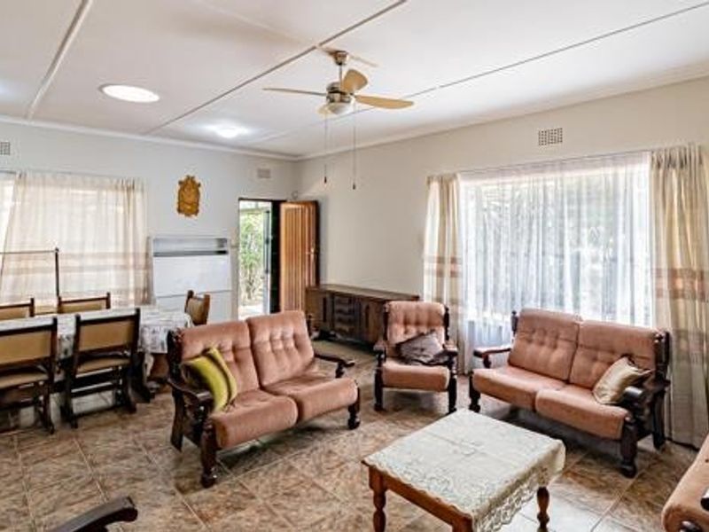 Spacious open-plan living and dining area featuring tiled flooring, a ceiling fan, and ample natural light through large windows.