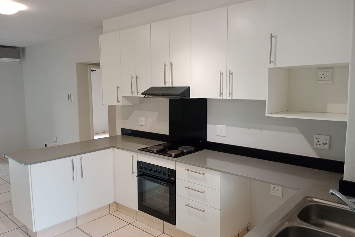 Modern kitchen featuring white cabinetry, stone countertops, built-in electric oven and stove, and tiled flooring in a clean, open-plan layout.