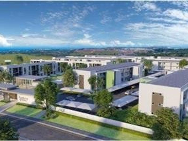 An aerial perspective of a modern apartment complex featuring multiple residential blocks, covered parking facilities, and landscaped outdoor areas.