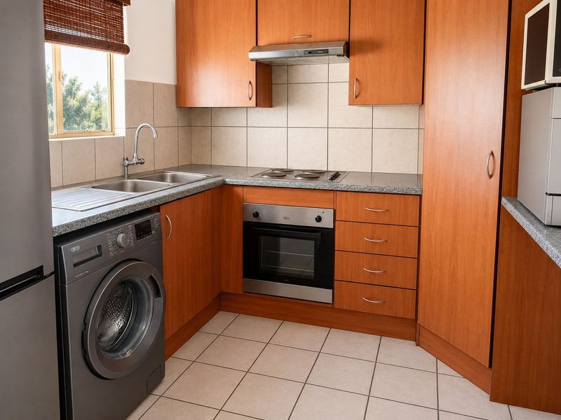 A functional kitchen featuring wood-finish cabinetry, granite-look countertops, built-in oven and hob, and tiled flooring with a neutral backsplash.
