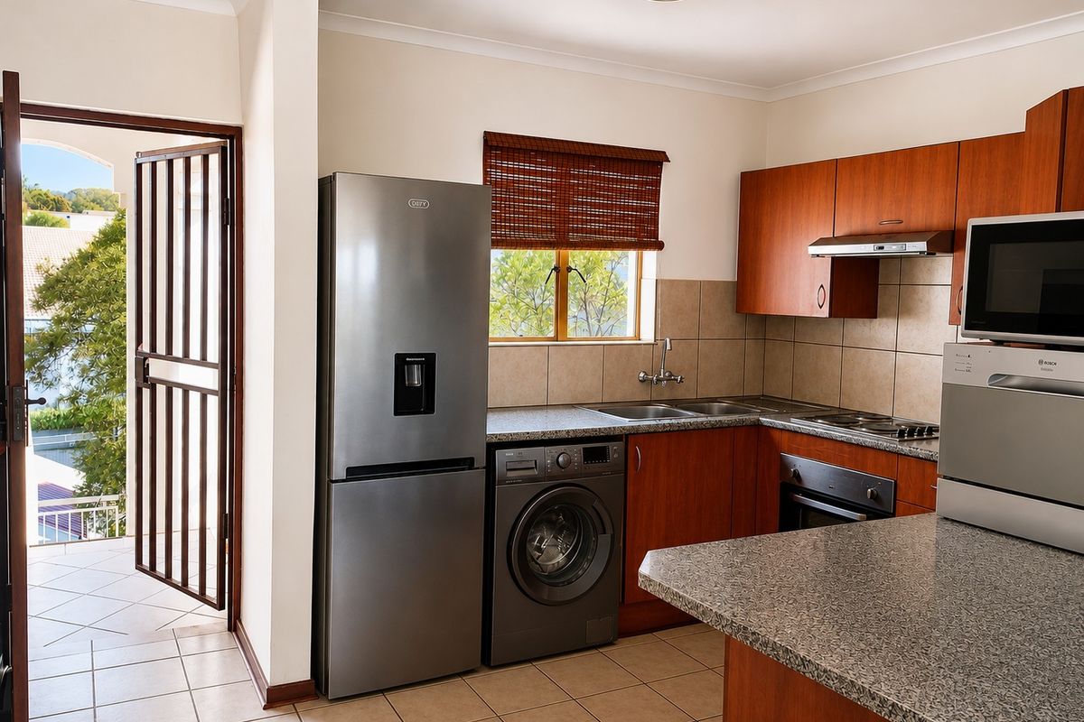Functional kitchen featuring granite countertops, wooden cabinetry, built-in oven, extractor fan, and tiled flooring, with direct access to an outdoor balcony area.