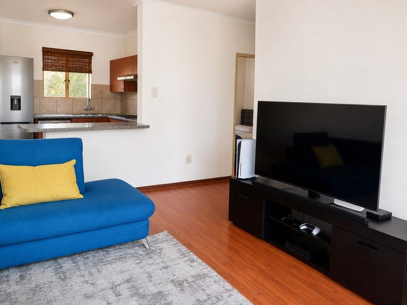Open plan living area featuring laminate flooring and a functional kitchen with granite countertops, built-in cabinetry, and a tiled backsplash.