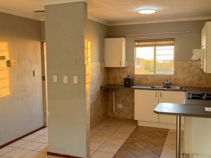 A functional kitchen featuring built-in cabinetry, a double sink, tiled splashbacks, and a breakfast bar, offering a clean canvas for potential updates.