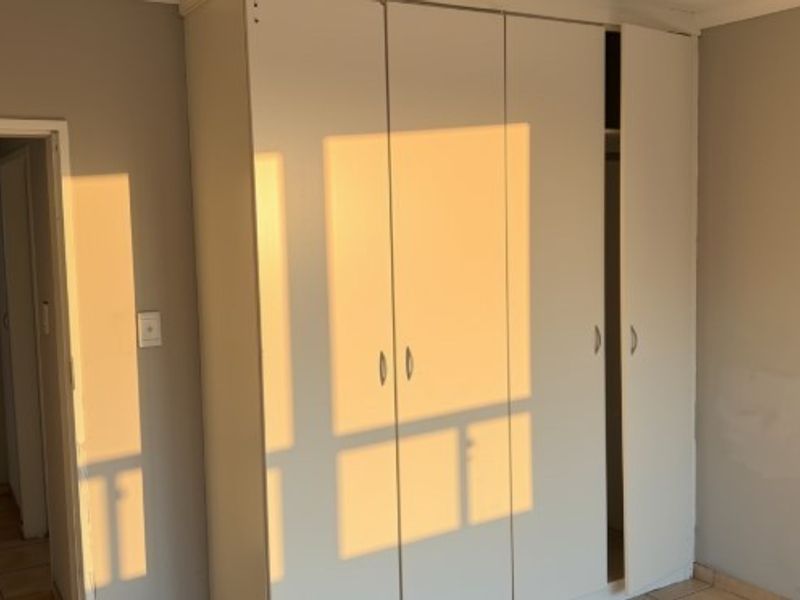 A bedroom featuring built-in wardrobes and tiled flooring, currently vacant and ready for personalization.