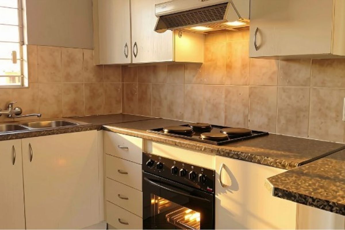 A functional kitchen featuring built-in cabinetry, laminate countertops, a double sink, and integrated cooking appliances including an oven, hob, and extractor fan.