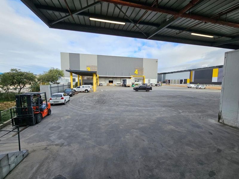 Spacious industrial yard area featuring a large warehouse facade with loading bays and a covered canopy structure.