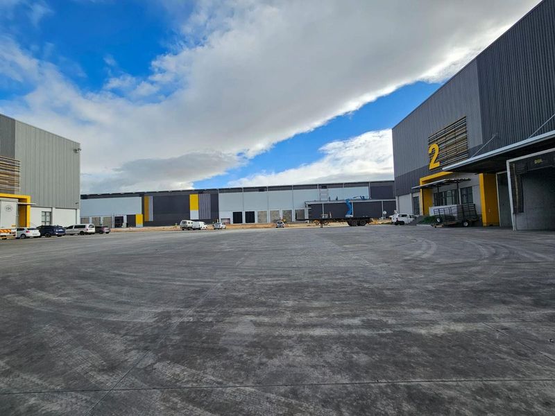 Spacious industrial concrete yard area serving multiple warehouse units with loading docks and modern metal cladding.