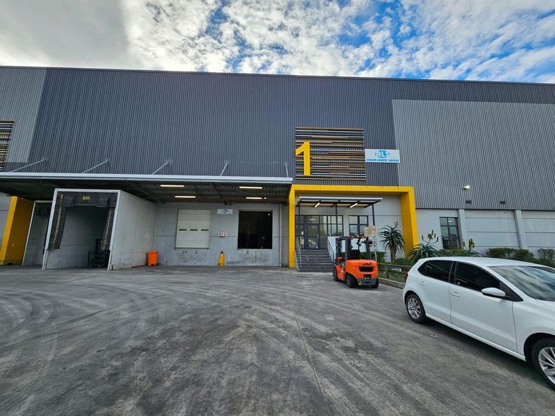 Industrial warehouse exterior featuring a loading dock with roller shutter door, concrete hardstand, and modern metal cladding facade.