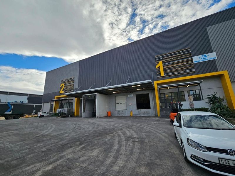 Industrial warehouse facility featuring multiple loading docks, roller shutter doors, and a paved concrete yard area suitable for logistics operations.