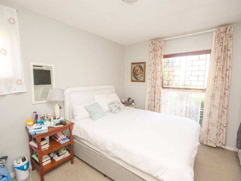 A functional bedroom featuring carpeted flooring and a window fitted with security bars, providing natural light and a standard layout.