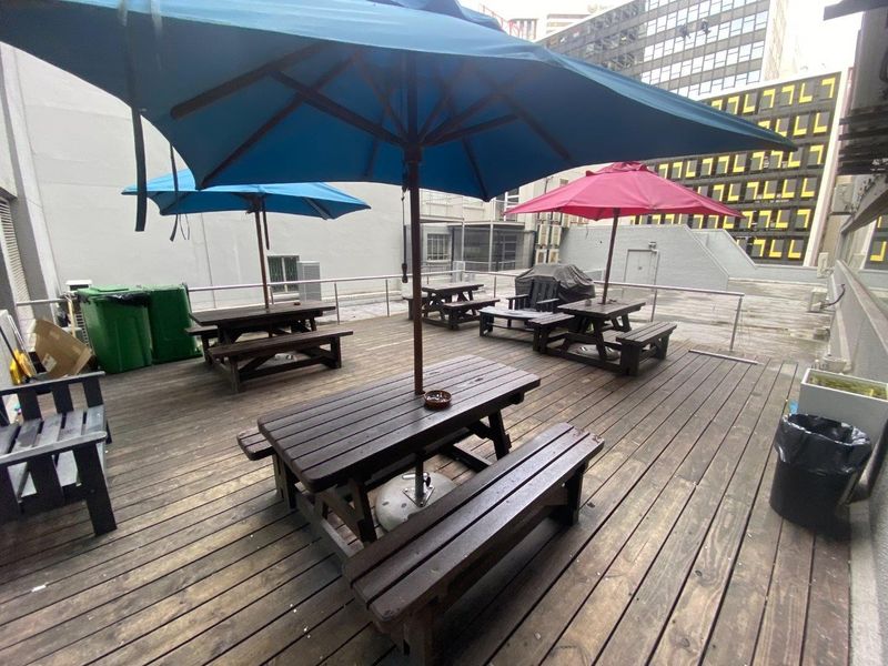 An outdoor commercial patio area featuring timber decking and metal safety railings, suitable for staff or client break-out space.