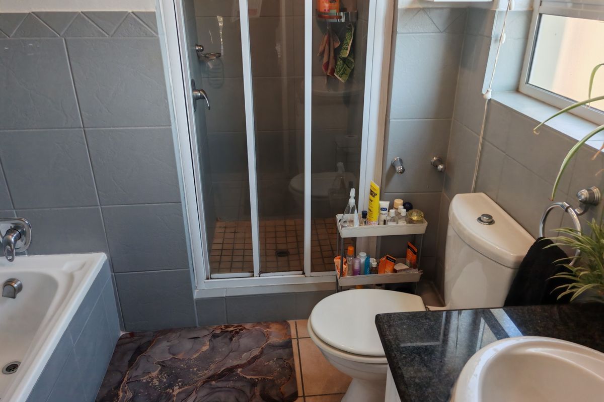 A functional bathroom featuring a separate shower enclosure, bathtub, toilet, and a vanity basin with a granite countertop.