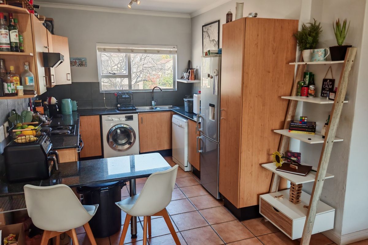 Functional kitchen featuring granite countertops, laminate cabinetry, tiled flooring, and integrated laundry plumbing, offering a practical layout for daily meal preparation.