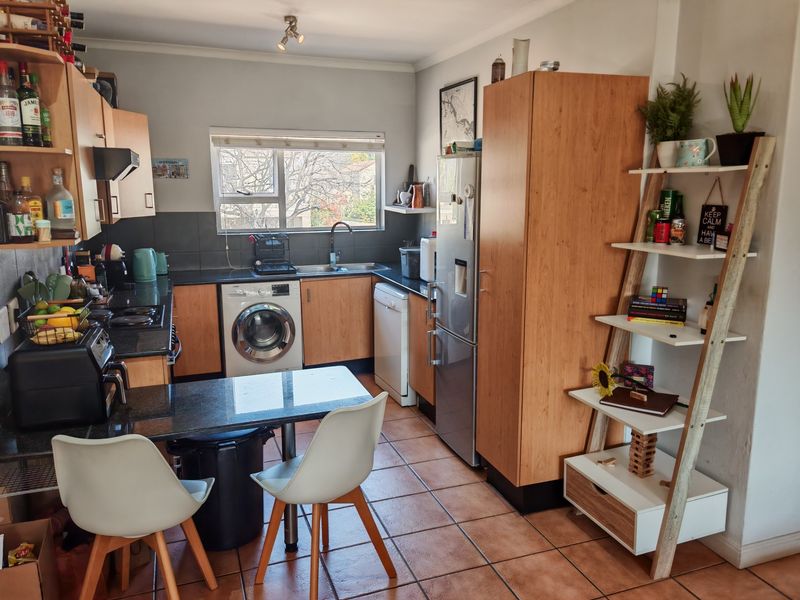 Functional kitchen featuring granite countertops, laminate cabinetry, tiled flooring, and integrated laundry plumbing, offering a practical layout for daily meal preparation.