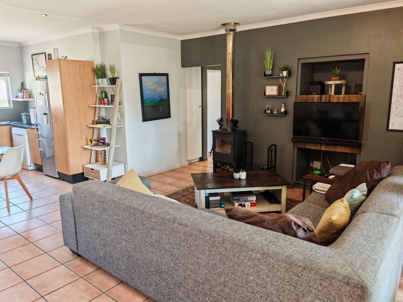Open-plan living area featuring a wood-burning fireplace, tiled flooring, and an integrated kitchen space, creating a functional and connected living environment.