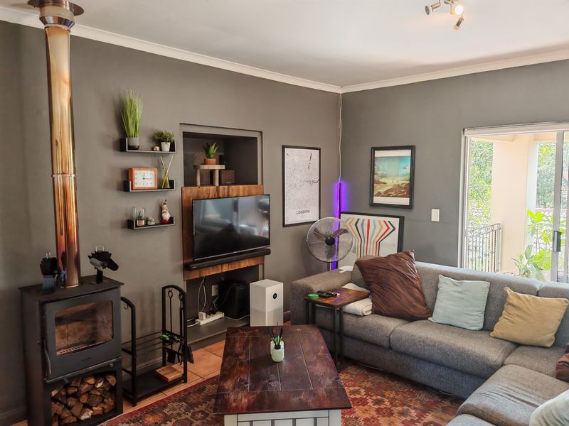 A cozy living room featuring a prominent wood-burning fireplace, a recessed wall niche for media, and direct access to an outdoor balcony.