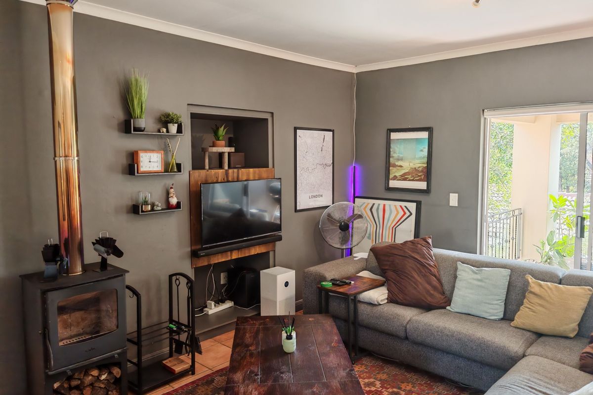 A cozy living room featuring a prominent wood-burning fireplace, a recessed wall niche for media, and direct access to an outdoor balcony.