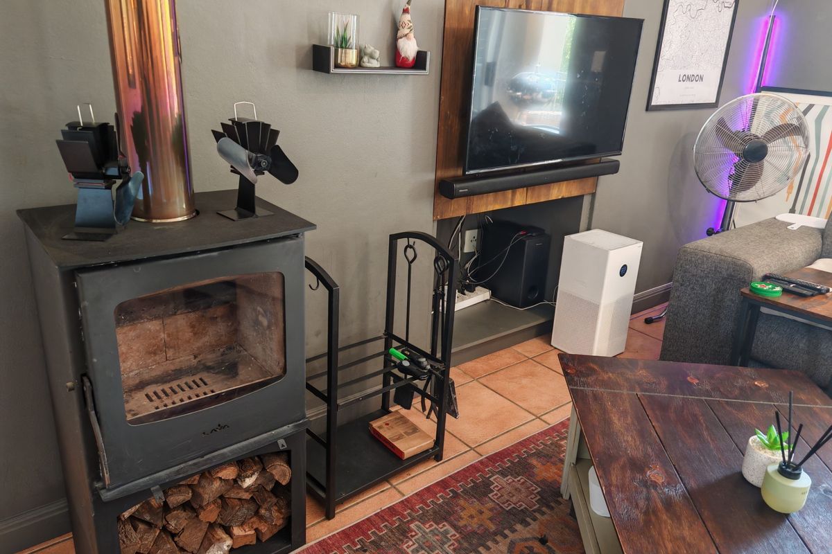 Living room featuring a freestanding wood-burning stove with a flue pipe and tiled flooring.