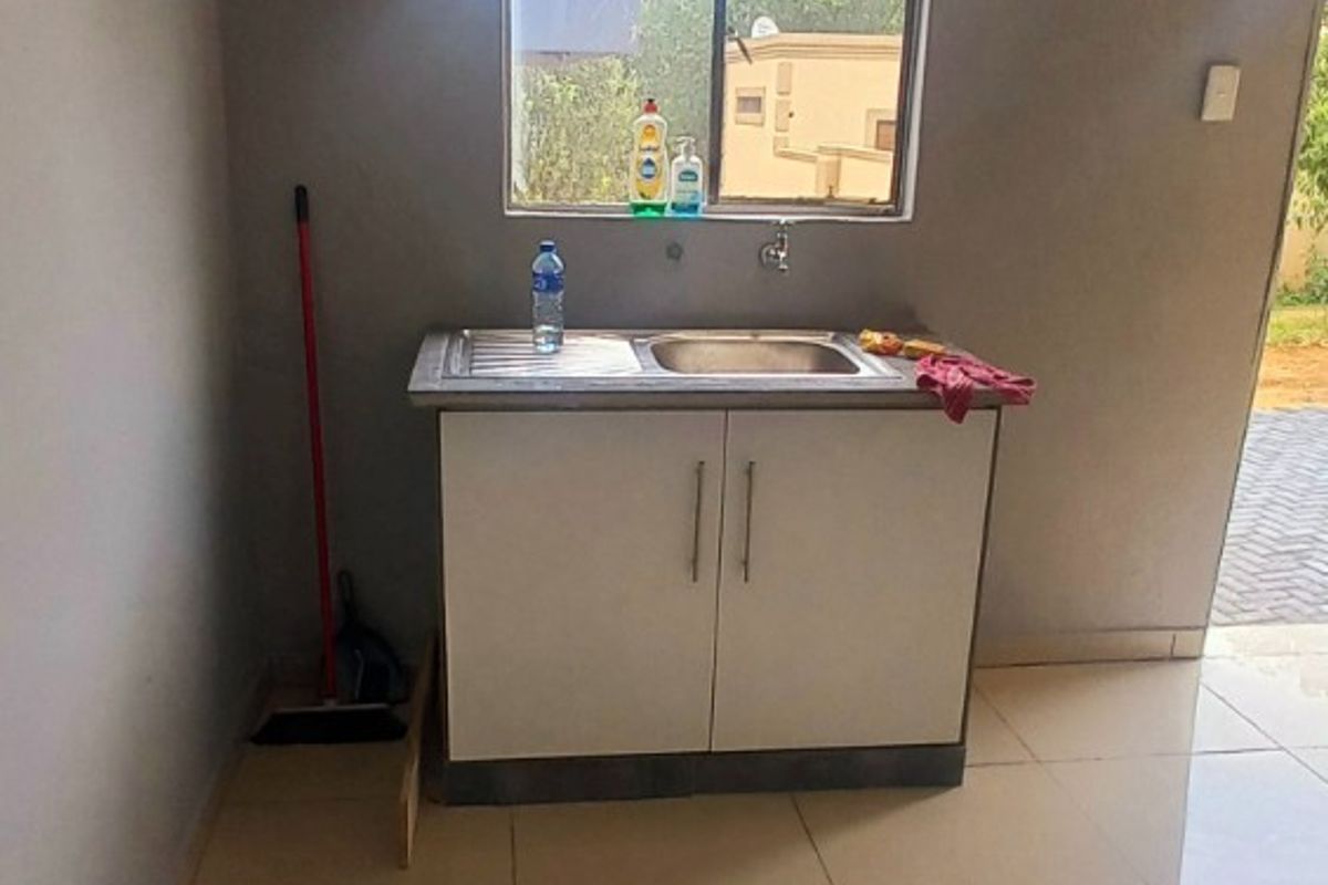 A compact kitchen area featuring a single stainless steel sink unit with base cabinetry and neutral tiled flooring.