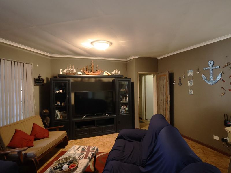 A living room featuring cork flooring, cove cornicing, and vertical blinds, providing a functional space with neutral wall tones.
