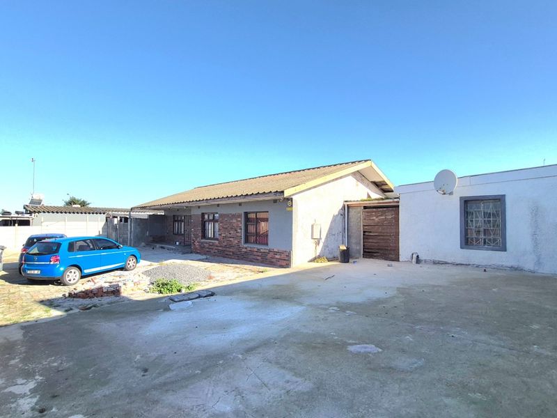 Front exterior view of a single-story house featuring a brick and plaster facade, concrete driveway, and security window bars.