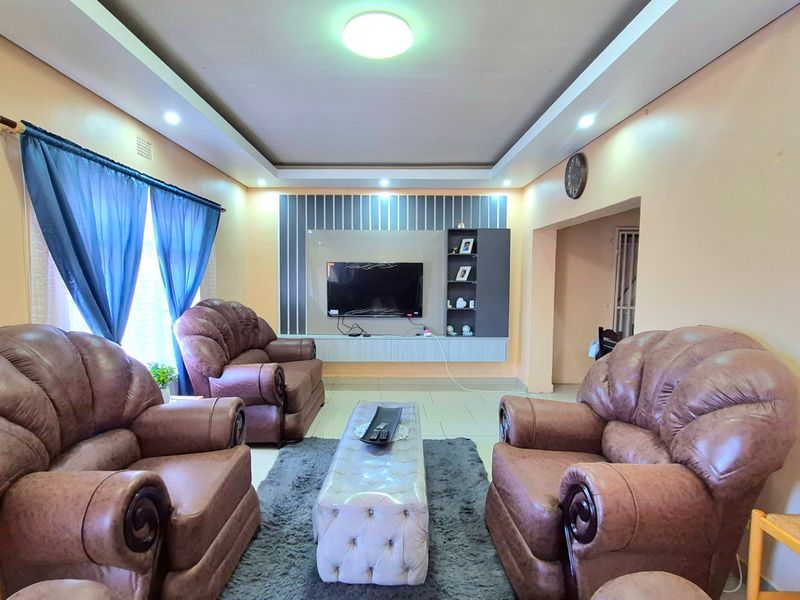 A living room featuring a recessed ceiling with integrated lighting and a built-in media wall unit with tiled flooring.